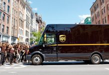 UPS truck with employees in brown uniforms on street.