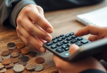 Person calculating savings interest with coins and calculator.