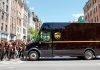 UPS truck with employees in brown uniforms on street.