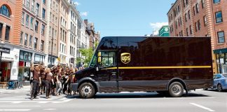 UPS truck with employees in brown uniforms on street.