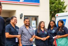 USPS employees engaging with customers outside a post office.