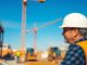 Construction worker on site with machinery and materials.