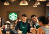 Starbucks baristas serving customers in a cheerful coffee shop.