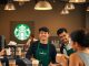 Starbucks baristas serving customers in a cheerful coffee shop.