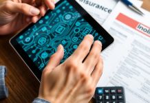 Hands using a tablet with blockchain patterns and insurance documents.