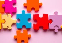 Colorful puzzle pieces interlocked on a soft gradient background.